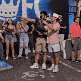 a group of people are standing in front of a wall with a crown and the letter t.