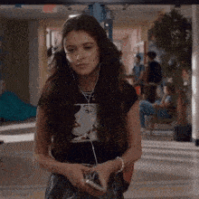 a woman wearing headphones is holding a cell phone .