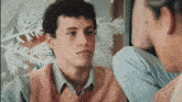 a man in a pink vest looks at another man
