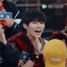 a young man is sitting in a crowd with his mouth open and people clapping .