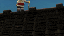 a lego man is standing on top of a roof next to a lego man with a beard