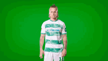 a man wearing a green and white hofmann jersey stands in front of a green screen