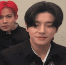 a man with red hair and a man with black hair are standing next to each other and looking at the camera .