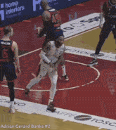 a basketball game is being played on a court with advertisements for home interiors in the background