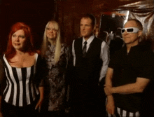 two women are standing next to each other and laughing . one of the women has red hair and the other has blonde hair .
