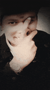 a man with a watch on his wrist is covering his face with his finger