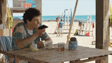 a man is sitting at a table looking at his phone