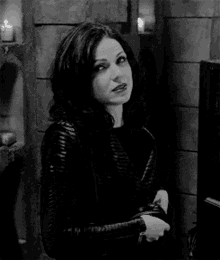 a black and white photo of a woman in a leather jacket standing next to a wall .