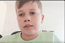 a close up of a young boy 's face with a green shirt on