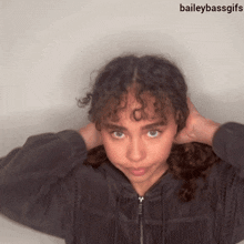 a girl with curly hair is wearing a black jacket