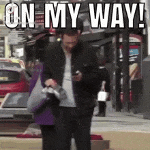 a man is walking down a street while looking at his phone and the caption says on my way