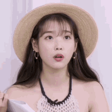 a woman wearing a straw hat and hoop earrings is making a surprised face
