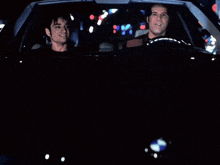 two men are driving a car at night and smiling