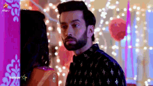 a man and a woman are standing next to each other in front of a purple wall with lights .
