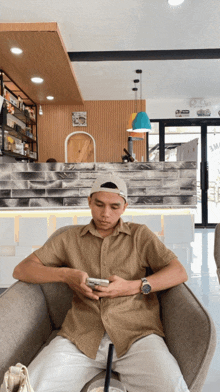 a man sits in a chair looking at his cell phone