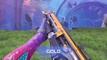 a person holding a gold colored gun in a field
