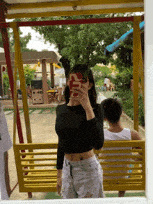a woman taking a picture of herself in a mirror with a phone that says supreme on it