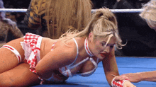 a woman is laying on the ground in a wrestling ring while a man holds her hand