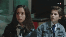 a boy and a girl are standing next to each other with trt 1 in the upper right corner