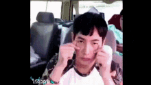 a man is making a funny face while sitting in the back seat of a car .
