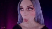 a woman with purple hair is making a funny face with her tongue out