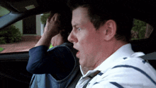 a man and a woman are sitting in a car and the man is looking surprised