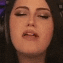 a woman is making a funny face with her eyes closed and her mouth open .
