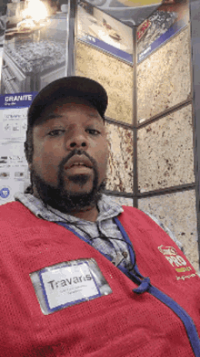 a man wearing a red vest and name tag that says travaris
