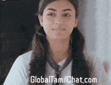 a girl is wearing a tie and smiling with the website globaltamilchat.com in the background .