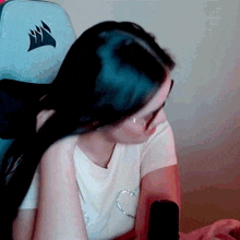 a woman is sitting in a chair with a corsair logo on the back of it