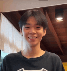 a young man wearing a black t-shirt is smiling for the camera .