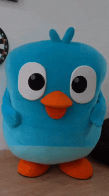 a blue stuffed bird with big eyes and orange feet