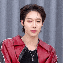 a young man wearing a red jacket and a necklace