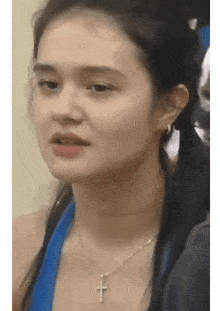 a young woman wearing a blue tank top and a cross necklace .