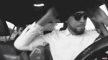 a black and white photo of a man in a car