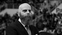 a bald man with a beard wearing a black suit and tie