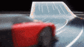 a red car is driving down a road with a curve