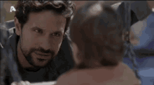 a man with a beard is looking at another man 's face