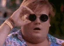 a fat man wearing sunglasses is looking through his glasses .