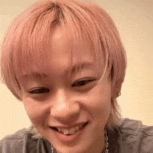 a close up of a person with pink hair smiling and looking at the camera .