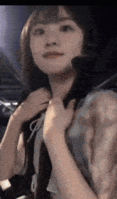 a close up of a woman adjusting her collar while looking at the camera .