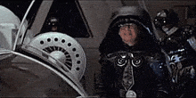 a man in a helmet is standing in front of a steering wheel in a vehicle .