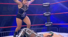 two women are wrestling in a ring and one of them is wearing a green outfit .