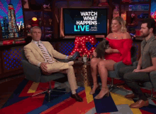 a group of people are sitting in front of a tv screen that says watch what happens live