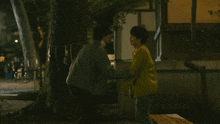 a man in a yellow jacket is hugging another man