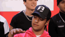 a man wearing a pink hoodie and a black hat with a picture of a horse on it