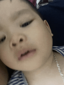 a close up of a baby 's face with a necklace on his neck