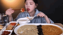 a woman is eating a meal with chopsticks and a spoon