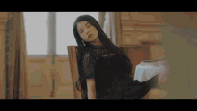 a woman in a black dress is sitting in a chair .