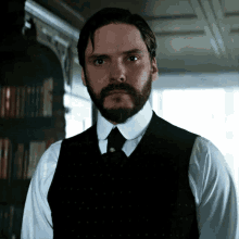 a man with a beard wearing a white shirt and black vest